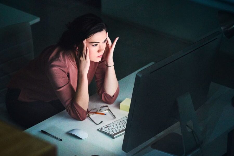 Girl looking frustrated and staring at screen in the dark