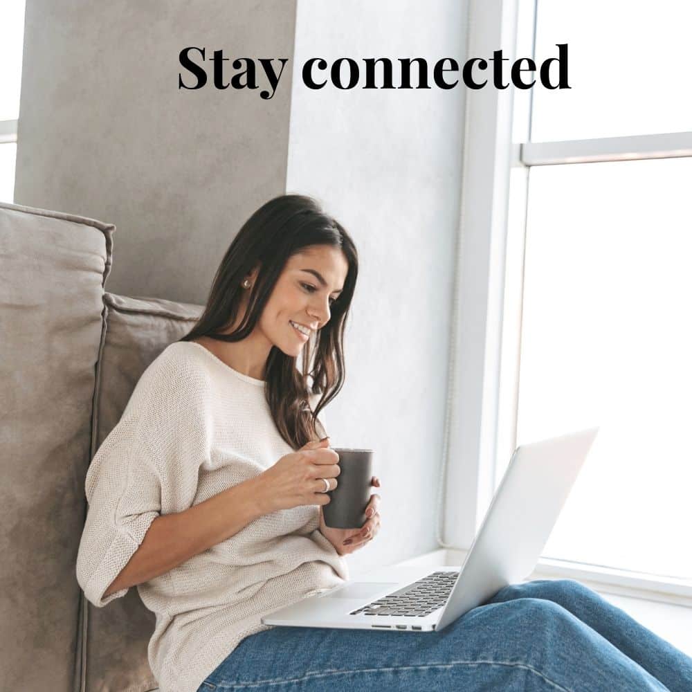 Woman drinking from a mug while smiling and reading her laptop