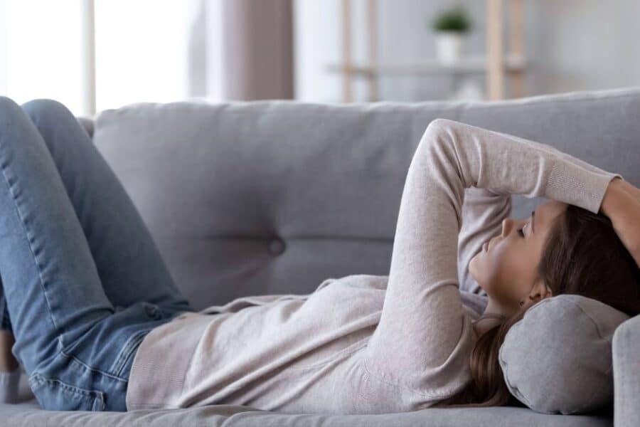 Woman lying on couch with arms overhead
